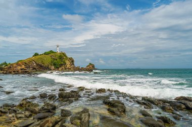 Güneşli bir günde, uçurumun kenarındaki deniz fenerinin manzarası. Beyaz deniz feneri, yeşil orman ve parlak gökyüzü. Mu Koh Lanta Ulusal Parkı, Tayland.