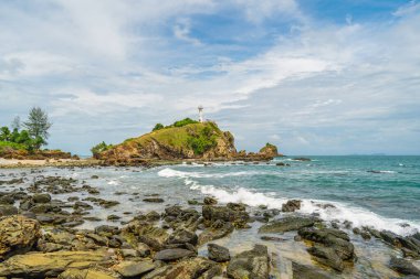 Güneşli bir günde, uçurumun kenarındaki deniz fenerinin manzarası. Beyaz deniz feneri, yeşil orman ve parlak gökyüzü. Mu Koh Lanta Ulusal Parkı, Tayland.