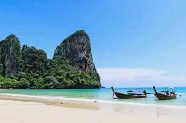 Tayland 'da uzun kuyruk tekneleri (Railay plajı). Kireçtaşı kayalıkları ve kristal berrak suyu olan güzel sahillerde tekneler..