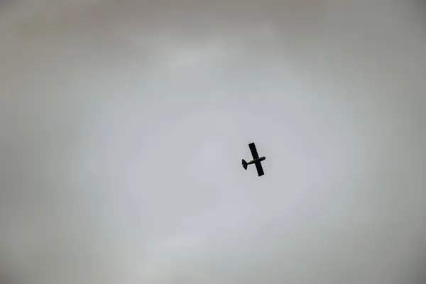 Gökyüzünde kara bulutlara karşı uçan küçük bir uçak. Uçuşun ortasında alçak açılı bir uçak görkemli bir şekilde havada süzülüyor..