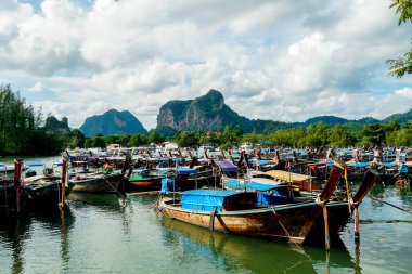 Tayland, Krabi 'deki Nopparat Thara sahilinde ve rıhtımda uzun bir tekne tersanesi. Tekne istasyonu ve yerel otantik tekneler dramatik bulutların altında gökyüzünde.