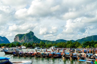 Tayland, Krabi 'deki Nopparat Thara sahilinde ve rıhtımda uzun bir tekne tersanesi. Tekne istasyonu ve yerel otantik tekneler dramatik bulutların altında gökyüzünde.