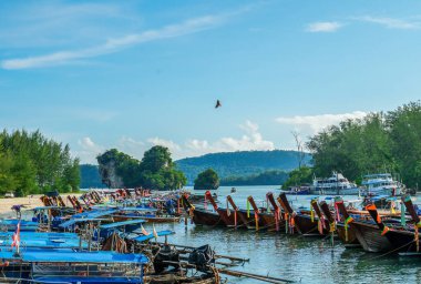 Tayland, Krabi 'deki Nopparat Thara sahilinde ve rıhtımda uzun bir tekne tersanesi. Tekne istasyonu ve yerel otantik tekneler dramatik bulutların altında gökyüzünde.