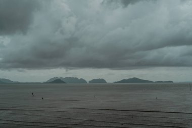 Tayland 'da güneş ışığı ışınları ve karanlık okyanus ile fırtına bulutları. Okyanus sahilinde güçlü bir dramatik fırtına hücresi. Tropikal bir sahilde kara fırtına bulutlarının altında kıyıya vuran dalgaların dramatik görüntüsü..