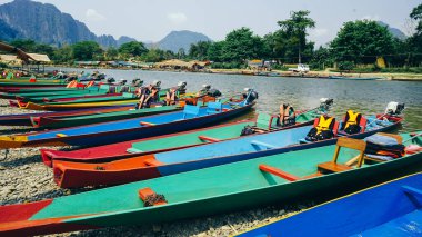 Uzun kuyruklu tekneler, Riverside 'da Boats Park Nam Song Nehri' nde turistleri bekliyor, Vang Vieng, Laos