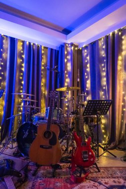 Kayıt stüdyosu. Müzik grubu provası. Modern bir müzik stüdyosu. Elektro gitarı, akustik gitarı, davul seti ve sandalyesi olan bir müzik stüdyosu..