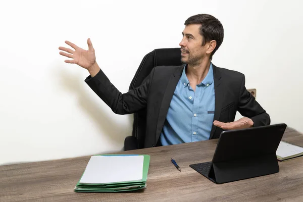 man in office presenting a new idea, with his open hand pointing to blank space on wall, new idea
