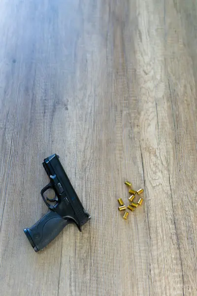 black pistol and bullets on a table, model Mp9 SW, copy space for message. it is an airsoft replica and the bullets are blanks.