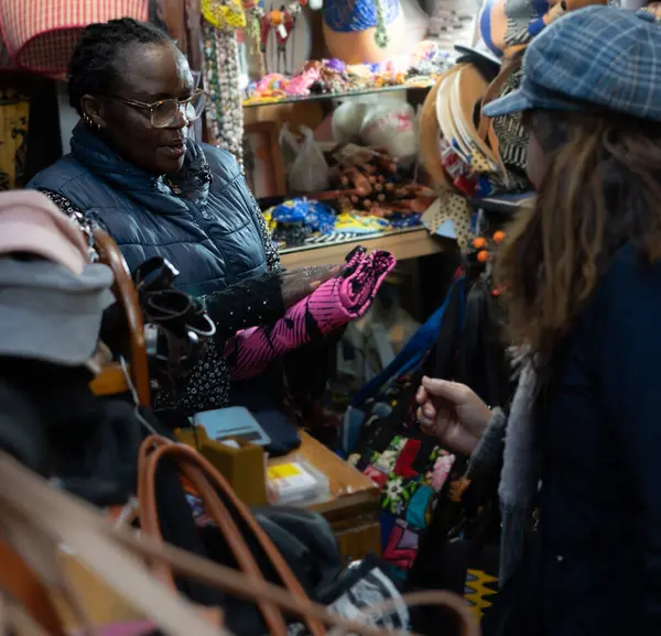 black grandmother selling a handbag to a customer in her African clothing store .