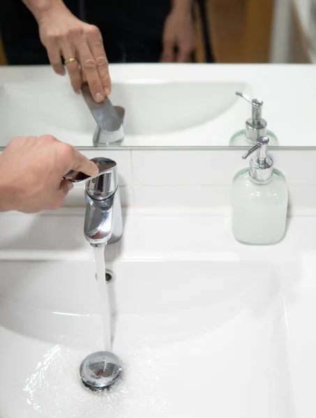 hand operating the sink water faucet. Water Restrictions and Water Resources Consumption