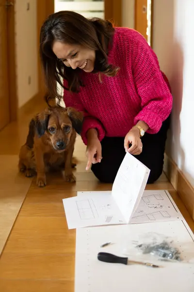woman teaches dog how to assemble a piece of furniture in her home. new families 2024