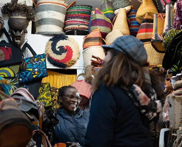 smiling African-American woman in her store selling African fair trade handicrafts to tourists.