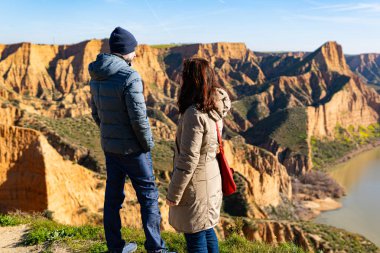 estranged angry couple think about their divorce in breathtaking scenery of mountains and red cliffs. Toledo Spain. clipart