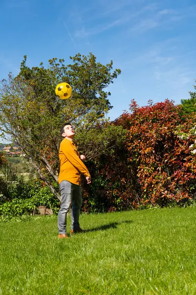 Casual and elegant dress with shirt, boots and boots. plays with a ball in a garden with trees enjoying himself