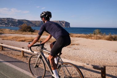 Denize yakın bisiklet süren profesyonel bir bisikletçi. İspanyol bisiklet tatili. Motivasyon imajı. Triatlon konsepti. Xabia, Alicante, İspanya