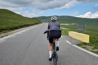 Dağ manzaralı bir yol bisikleti süren kadın bisikletçi. Rekabet için antrenman yapıyor. Açık kırsal yolda bisiklet sürüyor. Bucegi Doğal Parkı.