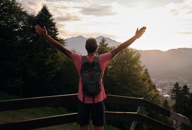 Yürüyüşçülerin gün batımına hayran kaldıkları arka manzara. Gün batımında ormanlı dağların ve tepelerin doğa manzarası. Dağ günbatımı izleyicisi..