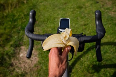 Bisiklet arka planında muz. Muz yiyen bisikletçi. Bir bisikletçinin sağlıklı beslenme şekli. Eğitim sırasında bir bisikletçi için sağlıklı atıştırmalık..