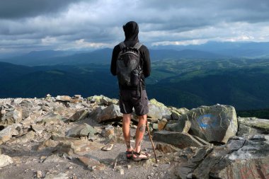 Dağın tepesinde duran yürüyüşçü güzel manzaranın tadını çıkarıyor. Dağlarda yürüyüş. Yürüyüş yapan turistlerle manzara