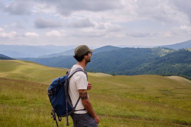 Sırt çantalı bir gezgin dağda yürüyüş yapıyor. Doğası gereği seyahat ediyor. Orta yaşlı bir adamın dağlarda yürüyüş yaparken çekilmiş dikiz görüntüsü..