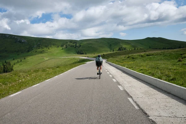Male cyclist on a gravel bike is riding on the road in the hills with a view of the mountains.Sport motivation image. Cycling holiday in Romania.