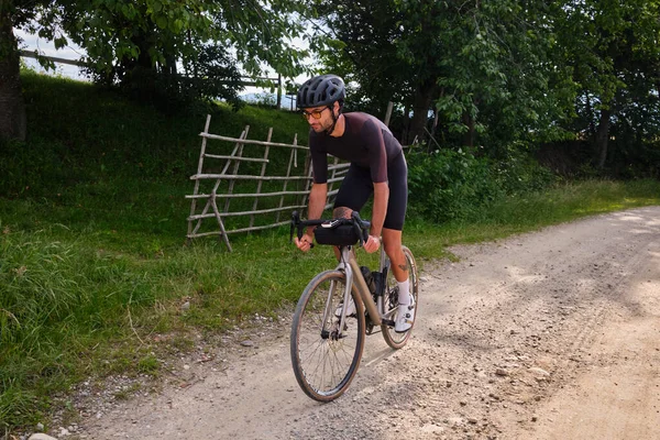Gravel biking. Male cyclist riding downhill by a gravel road. Man is cycling in the nature.