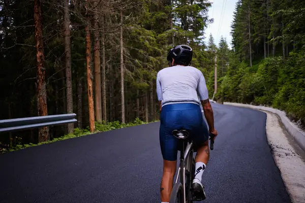 Profesyonel bir erkek bisikletçi boş bir orman yolunda bisiklet sürüyor. Bisiklet seti takan bir bisikletçi. Bisiklet eğitimi alıyordum. Yarışma için hazırlıklar.