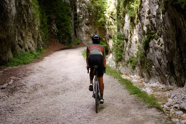 Male cyclist riding a gravel bike through rocky mountain terrain. Gravel biking adventure on beautiful mountain trails. Outdoor sport activity.