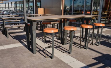 Kahverengi masalar ve açık kafe yakınındaki yemek için sandalyeler. Bir fast food restoranının yakınındaki sandalyeler ve masalar. Caddedeki kafe..