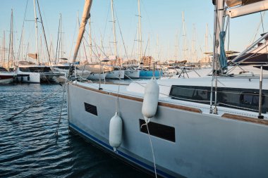 Gün batımında yat parkında. Günbatımında yatları olan deniz koyunda. Demirli yatlar. Marina, iskele. Gün batımında gemi direklerinin deniz suyuna yansıması. Torrevieja, Alicante, İspanya