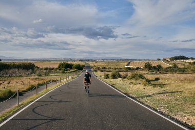 Günbatımında çakıllı bir bisiklete binen genç bir bisikletçi. Boş şehir yolu. İspanya 'da Murcia bölgesi.