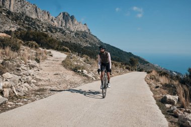 Bisiklet ve kask takan bir bisikletçi. Dağlarda bisiklet süren bir adam. Erkek bisikletçi dağlarda bisiklet sürüyor. Serra de Bernia, Alicante, İspanya