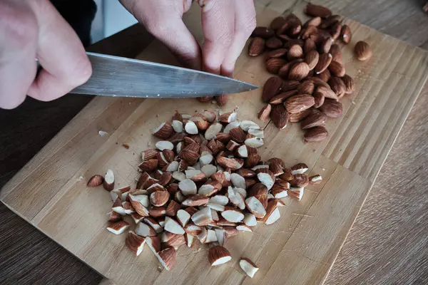 Kek için bademleri ince ince doğrayan bir kız eli. Bıçaklı ahşap mutfak tahtasıyla badem ezmesi. Bademli turta..