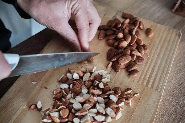 Kek için bademleri ince ince doğrayan bir kız eli. Bıçaklı ahşap mutfak tahtasıyla badem ezmesi. Bademli turta..