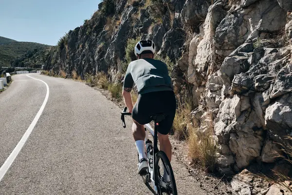 Male cyclist riding on a road bike in mountains.Man cyclist  wearing cycling kit and helmet.Beautiful motivation image of an athlete.Conquering the Vall de Ebo Pass on bicycle.Pego,Alicante,Spain.