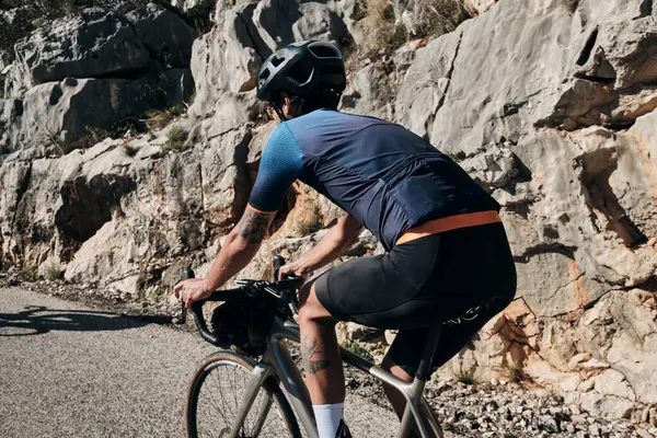 一个骑着砾石自行车的男子骑着马在山路上观赏着山水 骑自行车的人穿着自行车的工具和头盔 — 图库照片