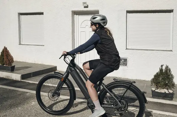 Elektrikli bisiklet macerası. E-bisiklet süren bir kadın bisikletçi yolculuğu. Bisiklet seti ve kask takan bisikletçi. Sağlıklı yaşam tarzı konsepti.