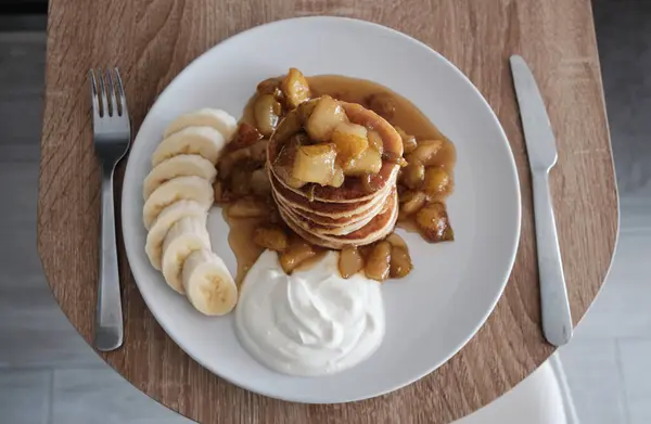 The perfect pancake breakfast.Fluffy pancakes with caramelized pear,yogurt, and bananas.Beautiful healthy breakfast.