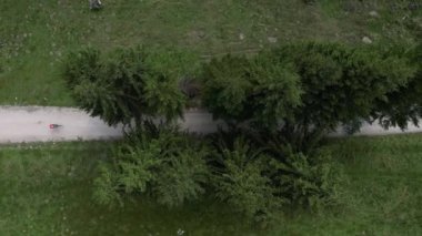 Dağ ağaçları arasındaki çakıllı yolda bisiklet süren bisikletli bir kadının insansız hava aracı görüntüsü. Açık hava antrenmanı. Çakıl bisikleti macerası. Toprak yolda bisiklet sürüyor. Transilvanya, Romanya