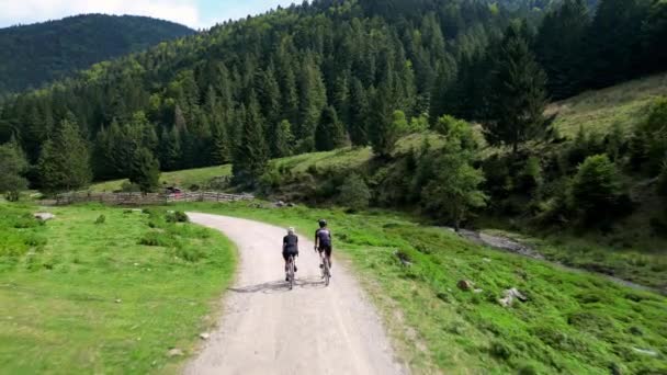 二人のサイクリストは 山の景色の美しさで砂利バイクに乗っています 砂利の道やオフロードでサイクリング アクティブな冒険と自転車での旅行のコンセプト 自然の中で自転車に乗る旅 — ストック動画
