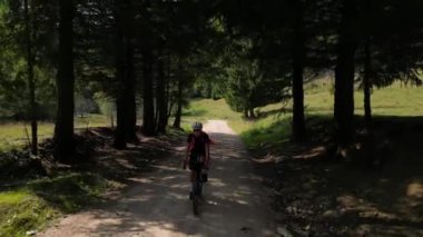 Kadın bisikletçi bir dağ ormanında çakıllı bir yolda bisiklet sürüyor. Açık hava antrenmanı. Çakıl bisikleti macerası. Toprak yolda bisiklet sürüyor. Transilvanya, Romanya