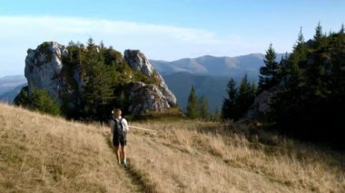 Aktif kadın dağa tırmanıyor. Dağın tepesinden doğa manzarasına hayran bir kadın sonbahar seyahatinin tadını çıkarıyor. Yürüyüş. Rahatla, doğa özgürlüğü. Dağlarda yürüyüş yapan.