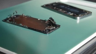 Yakın plan çekimde cep telefonu tamirini gösteriyor. Teknisyen telefonu tamir ediyor. Akıllı telefonu tamir ediyorum ve cep telefonu detaylarını güncelliyorum. Parçalanmış cep telefonu. Bir akıllı telefonun iç bileşenleri.