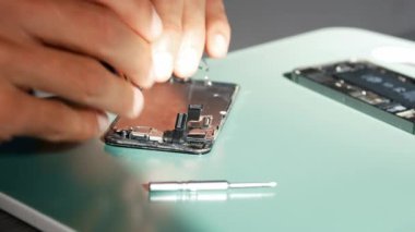 Yakın plan çekimde cep telefonu tamirini gösteriyor. Teknisyen telefonu tamir ediyor. Akıllı telefonu tamir ediyorum ve cep telefonu detaylarını güncelliyorum. Parçalanmış cep telefonu. Bir akıllı telefonun iç bileşenleri.