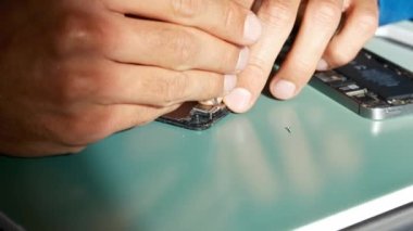Yakın plan çekimde cep telefonu tamirini gösteriyor. Teknisyen telefonu tamir ediyor. Akıllı telefonu tamir ediyorum ve cep telefonu detaylarını güncelliyorum. Parçalanmış cep telefonu. Bir akıllı telefonun iç bileşenleri.