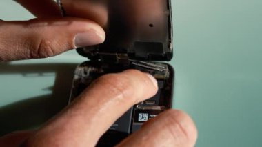 Teknisyenlerin tamir işlerini kapatın ya da masadaki bozuk ve hasarlı akıllı telefonun yeni parçalarını değiştirin. Telefon ve ekipman tamiri için atölye çalışması. İşçi akıllı telefonun servisini yapar..