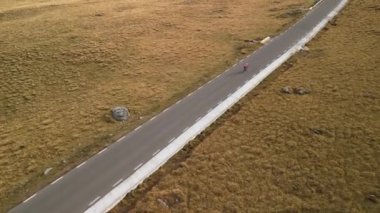 Boş dağ yolunda bisiklet süren profesyonel kadın bisikletçinin hava aracı görüntüsü. Aktif spor konsepti. Açık havada bisiklet sürmek. Bisiklet üzerinde egzersiz. Bisiklet sürmek ve sağlıklı yaşam tarzı kavramı.