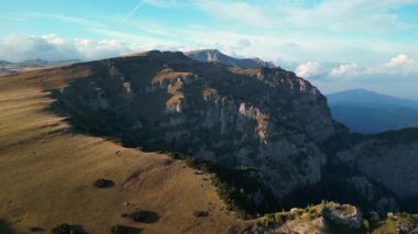 Dağlarda gün batımı. Destansı dağların üzerinde İHA uçurmak. Rocky Dağları yemyeşil bitki örtüsüyle kaplıdır. Karpat Dağları. Bucegi Doğal Parkı, Romanya.
