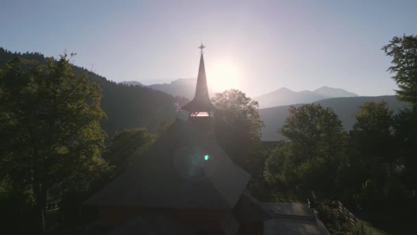 日没のルーマニアの山村にある木製の正統派教会を経由した無人機の飛行の空中映像 木製の正統派教会 神聖な宗教的な場所 古代ルーマニア正教会 Azuga ルーマニア — ストック動画