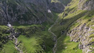 Romanya 'nın güzel dağları arasındaki vadi manzarası. Destansı dağların üzerinden uçuyor. Yeşil çayır ve keskin kayalarla kaplı dağ manzarası. Bucegi Doğal Parkı. Romanya